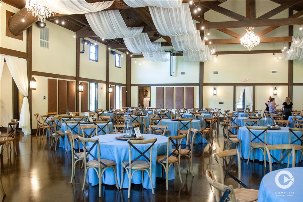 BARN AT BAY HORSE INN WEDDING VENUE GREENWOOD INDIANAPOLIS INDIANA TABLES SET IN BLUE WITH BEAUTIFUL CEILING TREATMENTS