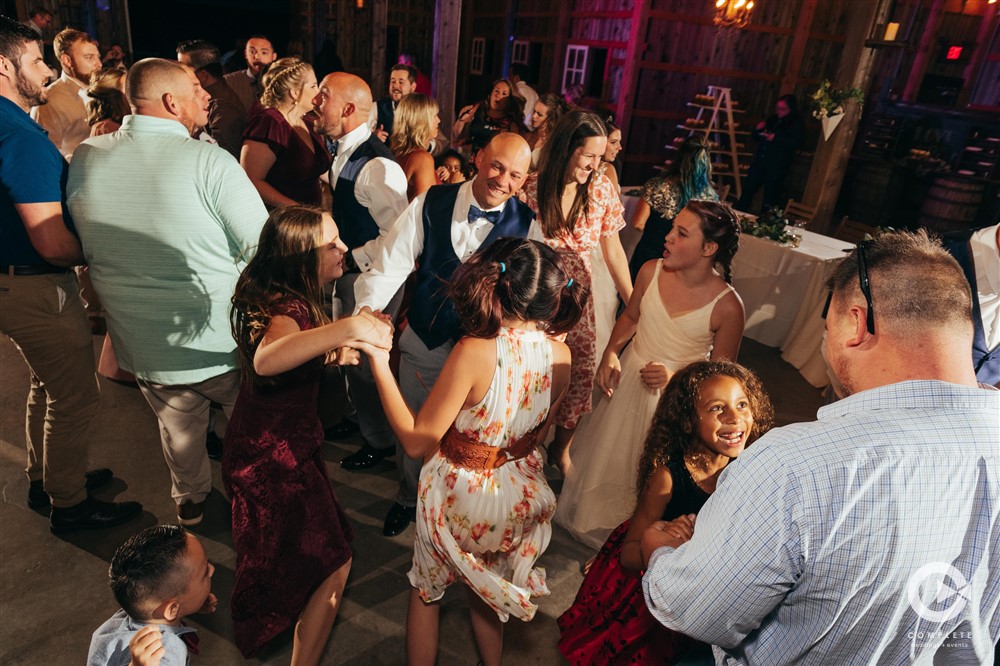WEDDING MUSIC MISTAKES TO AVOID GROOM SURROUNDED BY FRIENDS AND FAMILY ON DANCE FLOOR AT WEDDING INDIANAPOLIS