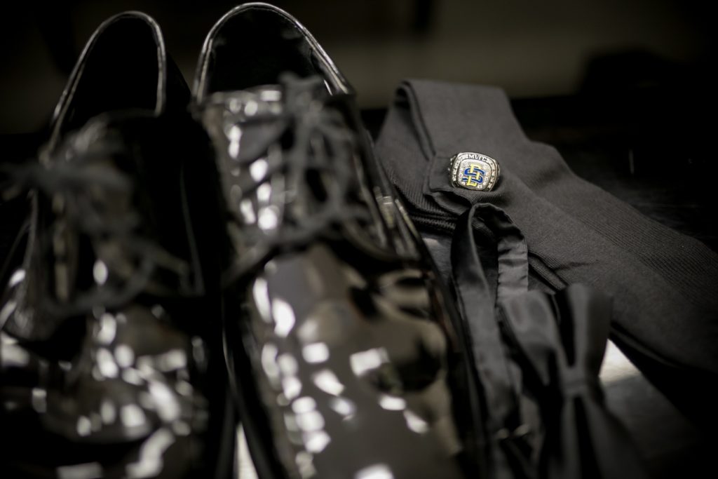 Detail photo of groom's black shiny shoes, ring, socks and bow tie.