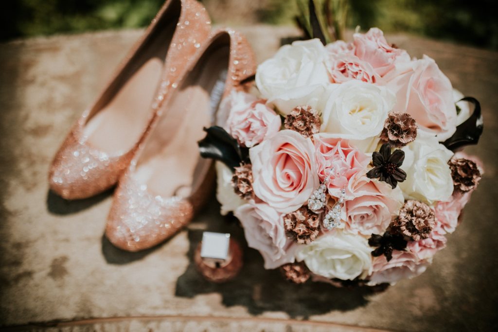 The bride's sparkly pink colored shoes and matching her bouquet of pink and white roses.
