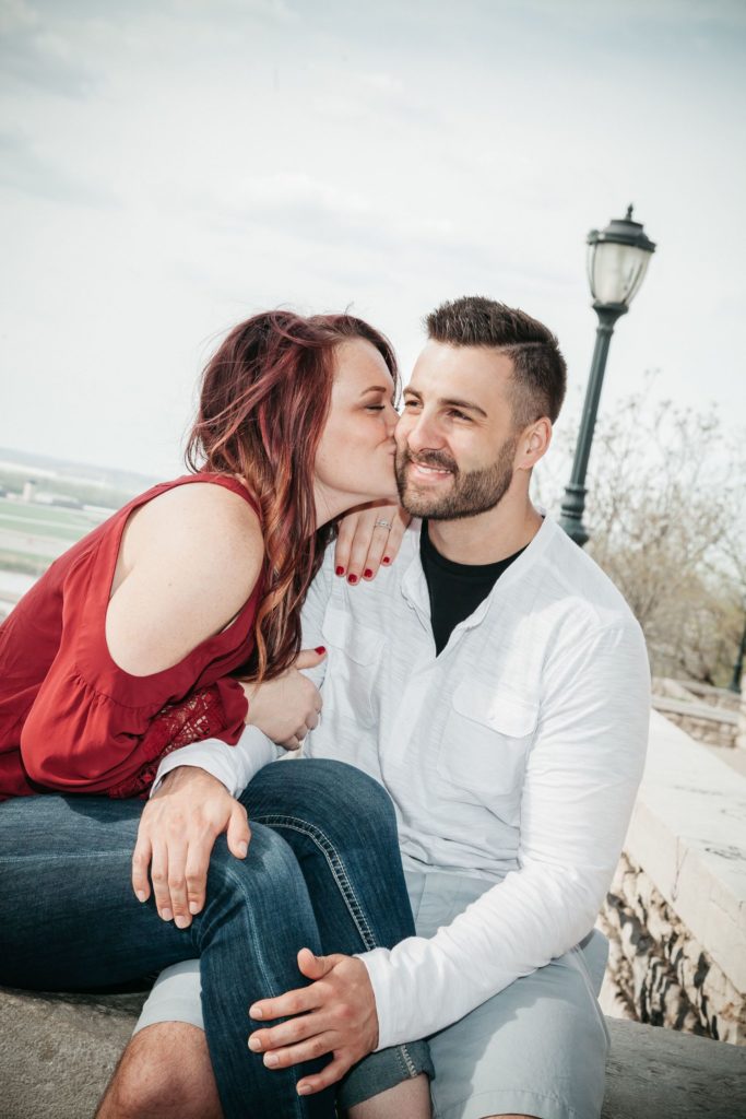 Newly engaged couple pose on a bridge together