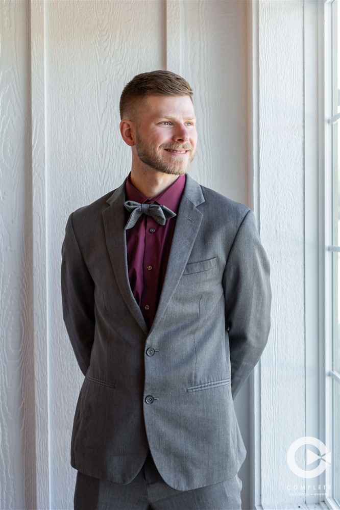 groom wearing grey suit with maroon