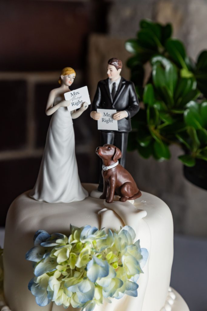 Wedding cake topper of a bride and groom with their dog at a wedding near Kansas City.
