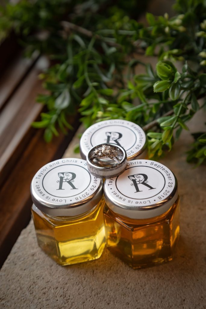 Wedding rings sitting atop jars of jelly used as wedding favors for guests.