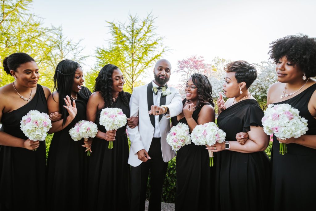 Groom poses with bridesmaids at Loose Park in Kansas City