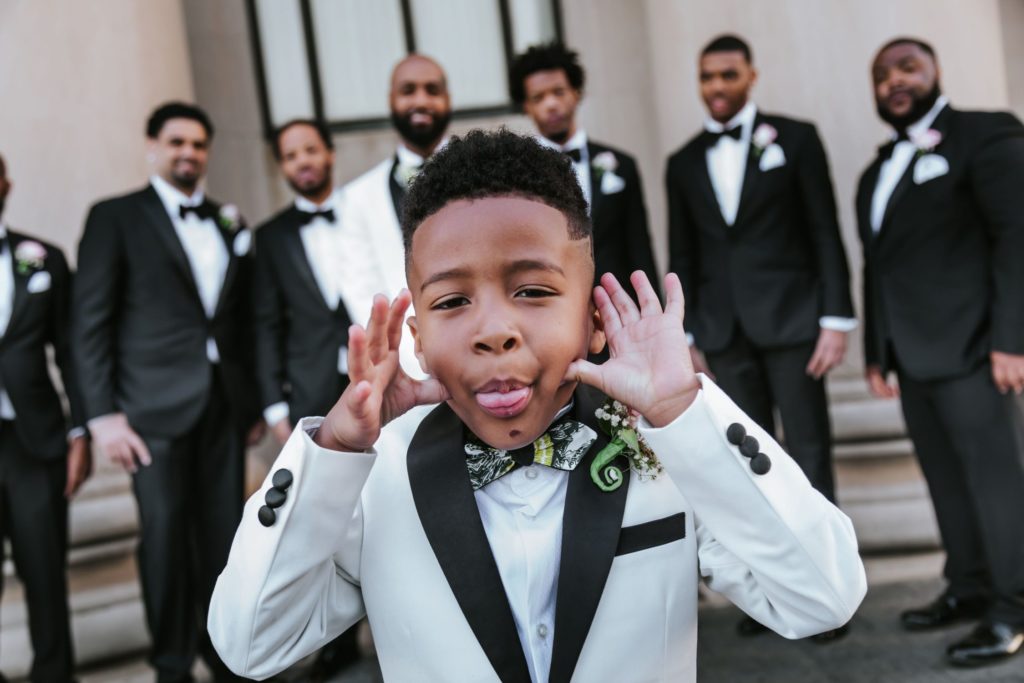 Close up of ring bearer with groom and groomsmen in the background