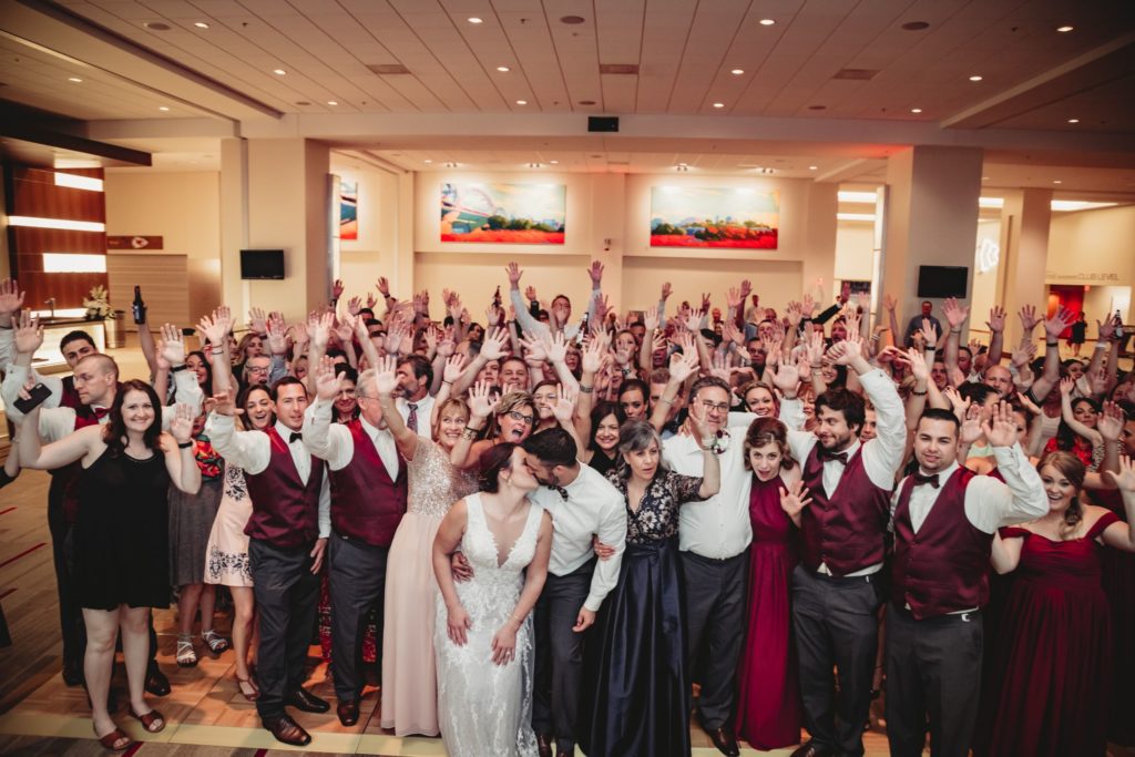 Bride and groom pose in front of all their guests and share a kiss