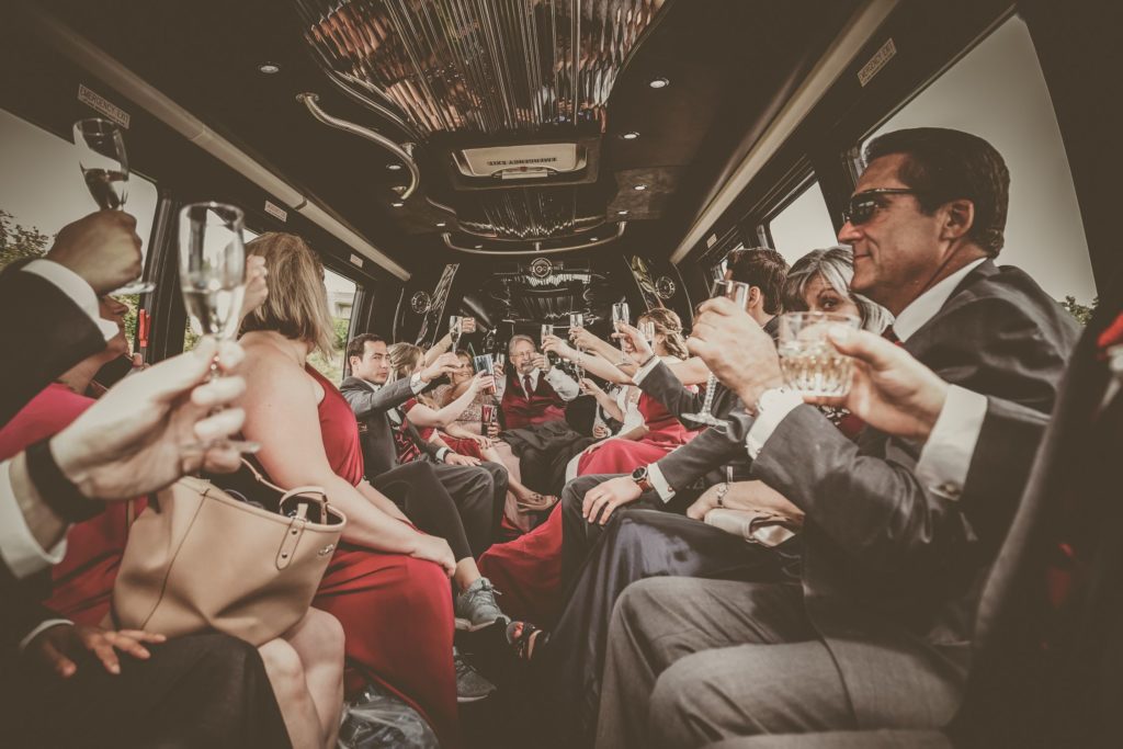 Bride and groom share a limo ride with wedding party who are toasting the new couple
