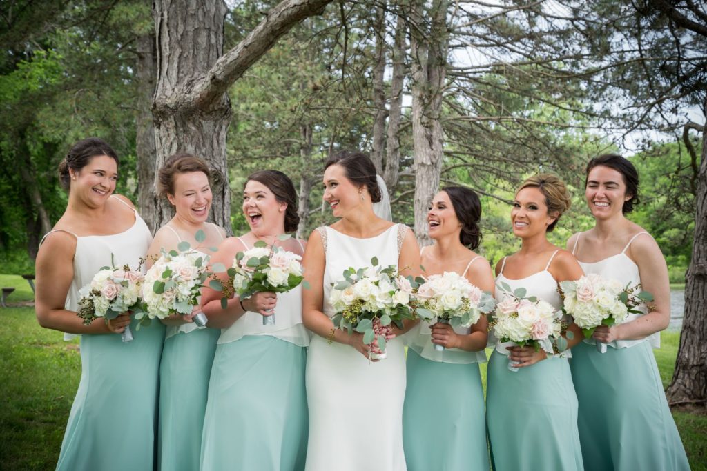 Bride with her bridesmaids that are wearing sage colored dresses in a spring wedding