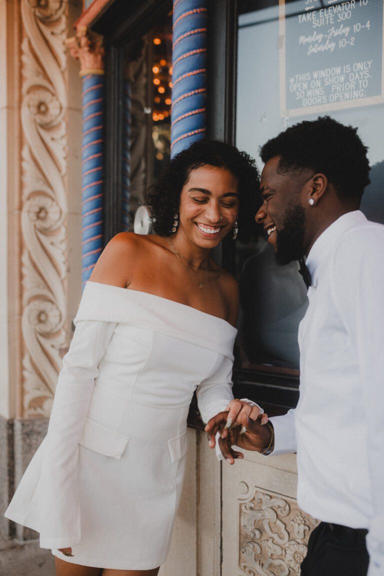 Engaged couple sitting together on a stone ledge in downtown Kansas City during their Uptown Theater engagement session photographed by Kansas City wedding photographer Gabriel with Complete Weddings and Events