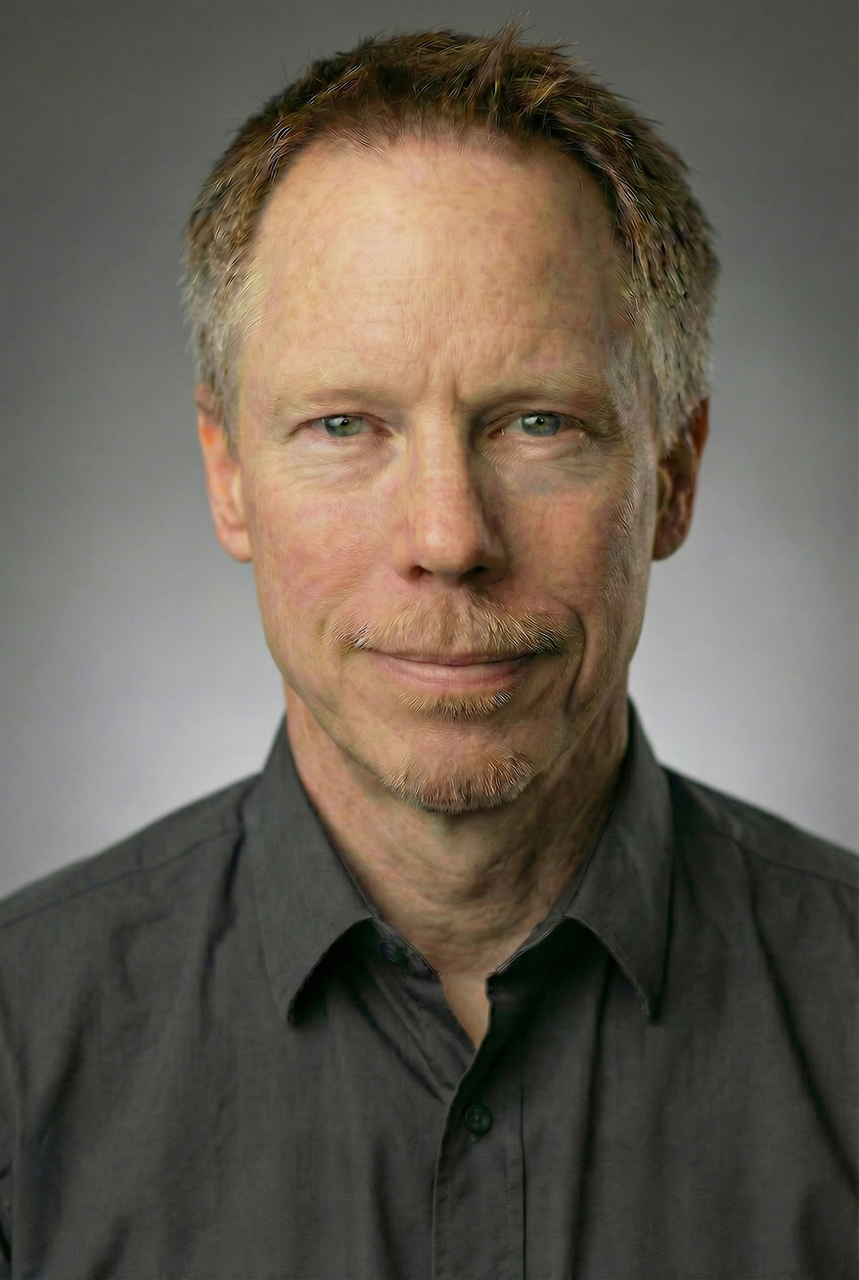 Headshot of Josh, a videographer for Complete Weddings and Events, wearing a dark shirt against a gray studio background.