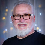 Kansas City wedding videographer Donny wearing a Kansas City Crawfish Festival shirt in front of soft colorful lights