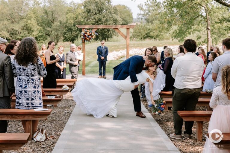 Groom dipping bride for a kiss in the ceremony aisle at Tobacco Barn Farm wedding venue near Kansas City photographed by Complete Weddings and Events photographer Kim Miller