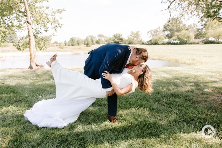 Romantic dip‑kiss by the pond at Tobacco Barn Farm, photographed by Kim Miller with Complete Weddings & Events.