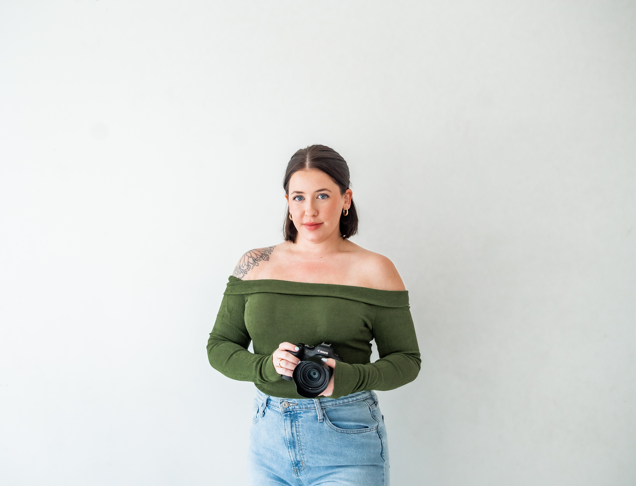 Kansas City wedding photographer Sophie holding her camera in a bright portrait