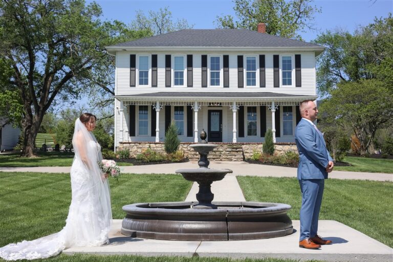 Bride and groom first look by the fountain in front of the white farmhouse at Whiskey Ridge wedding venue in Tonganoxie, KS