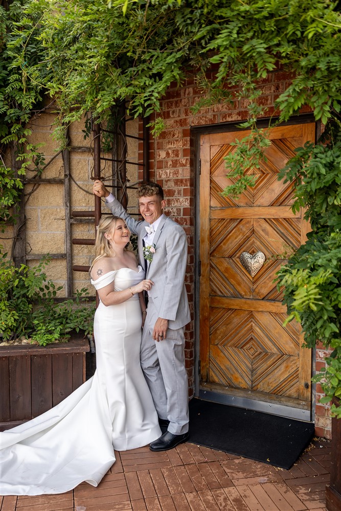 Groom twirls his bride under a wisteria-covered brick doorway at The Stanley in Lee's Summit, Missouri