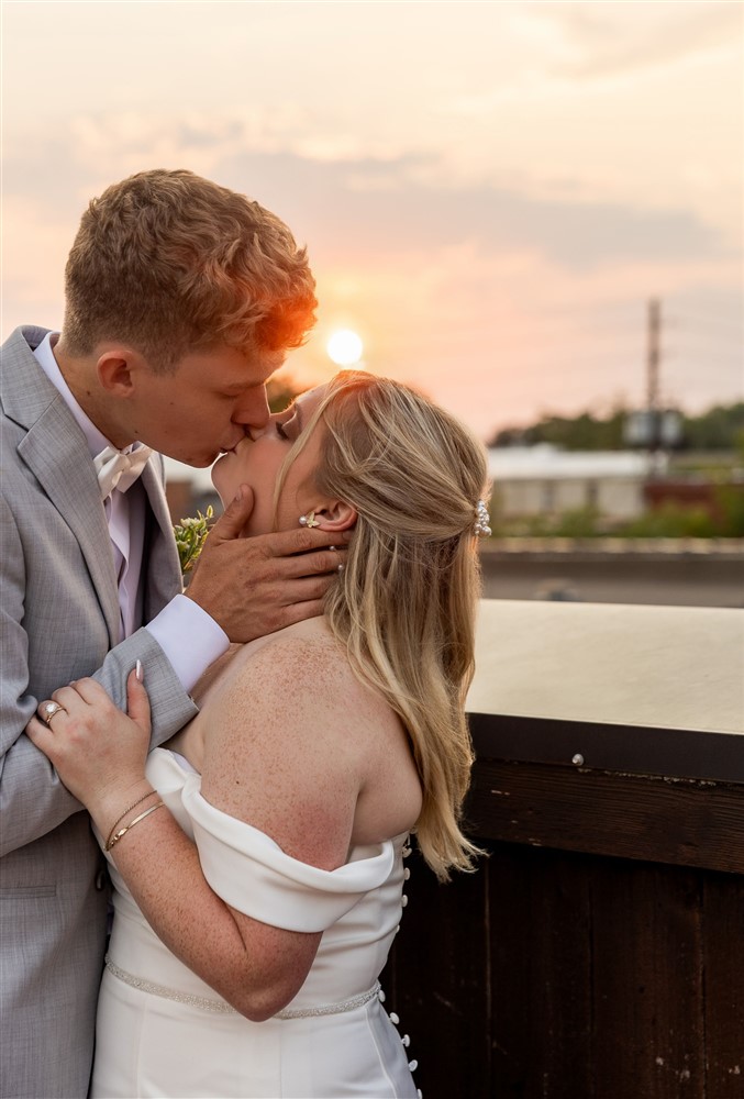 Bride and groom kiss at sunset on the rooftop terrace at The Stanley in Lee's Summit, Missouri