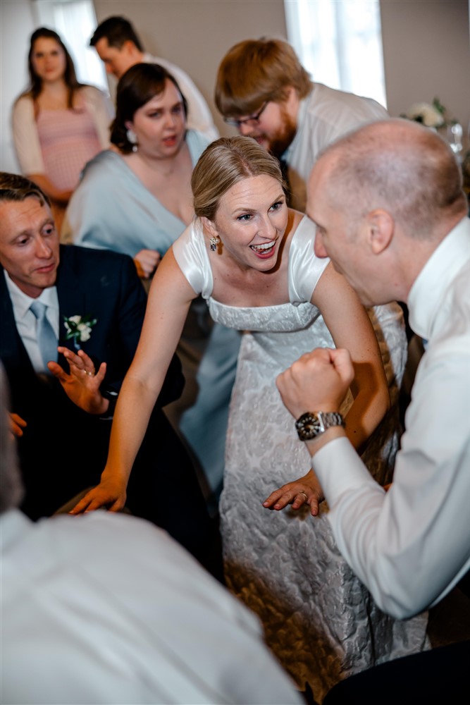Bride laughing on a packed dance floor surrounded by wedding guests at an Overland Park, Kansas wedding reception