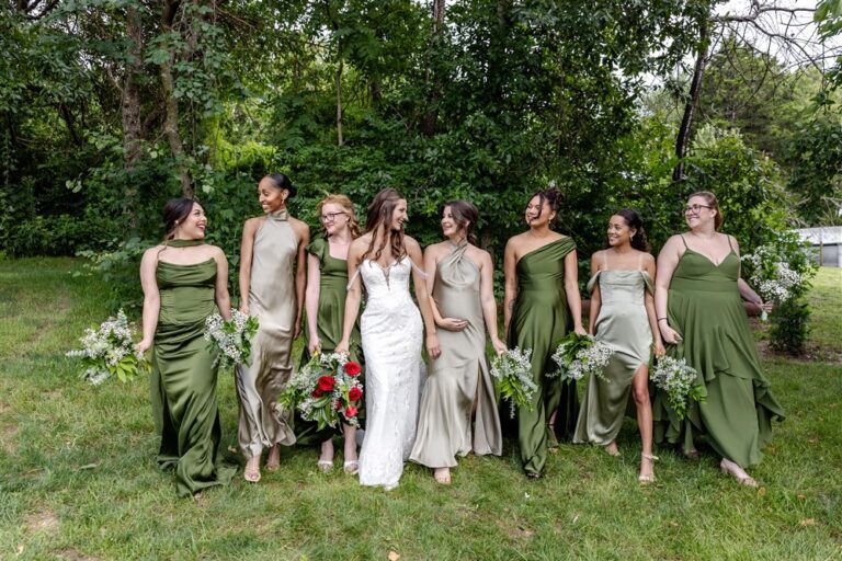 Bride walks through the grass with eight bridesmaids in olive and sage green gowns at a private residence wedding in Blue Springs, Missouri