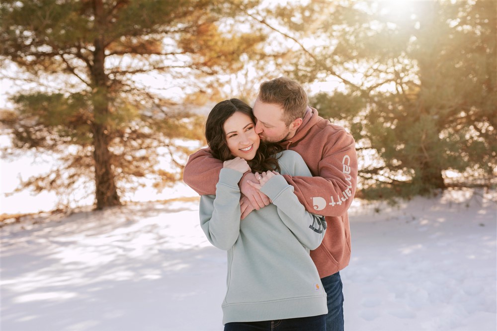Engagement photo with sun peeking through trees during winter