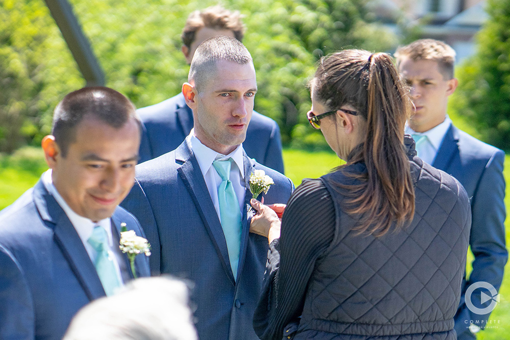 wedding planner assisting groomsmen with boutonnière