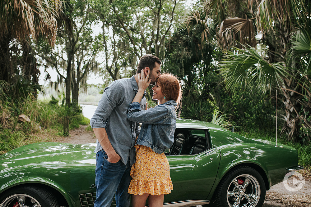 engaged couple kiss in front of green car