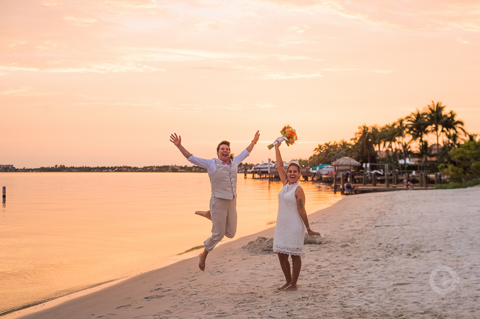 Newlyweds leap for joy on Beach during golden hour sunset - 