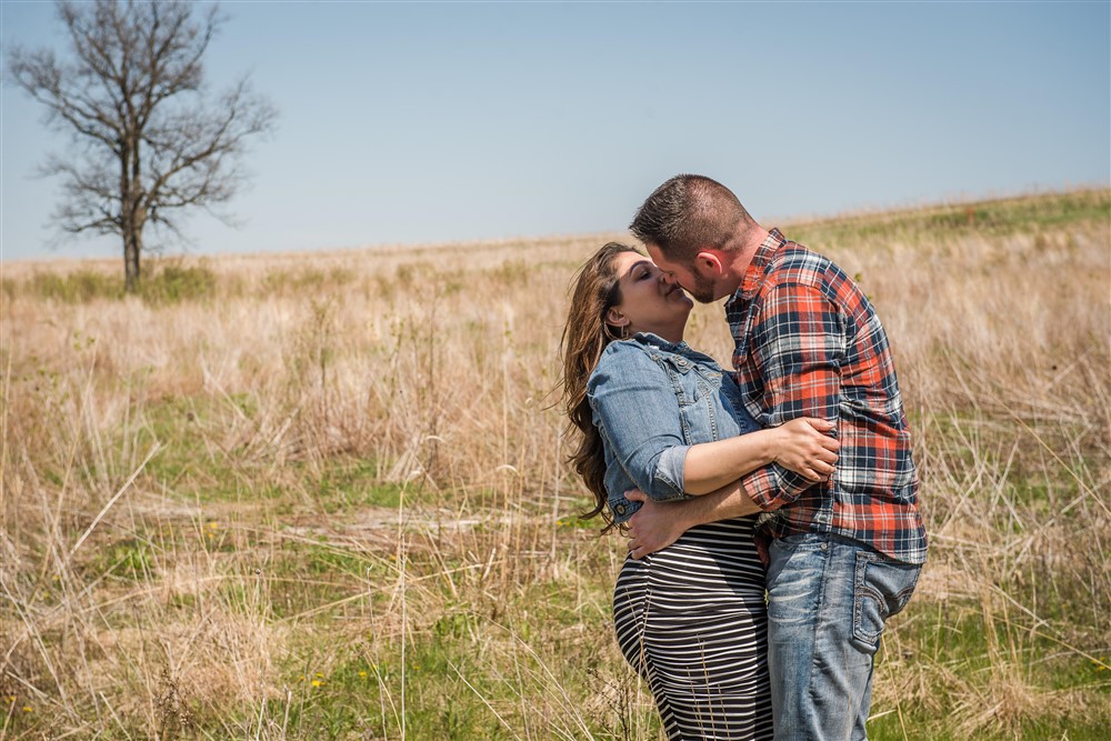 Couple kissing in field in outdoor engagement shoot in Milwaukee
