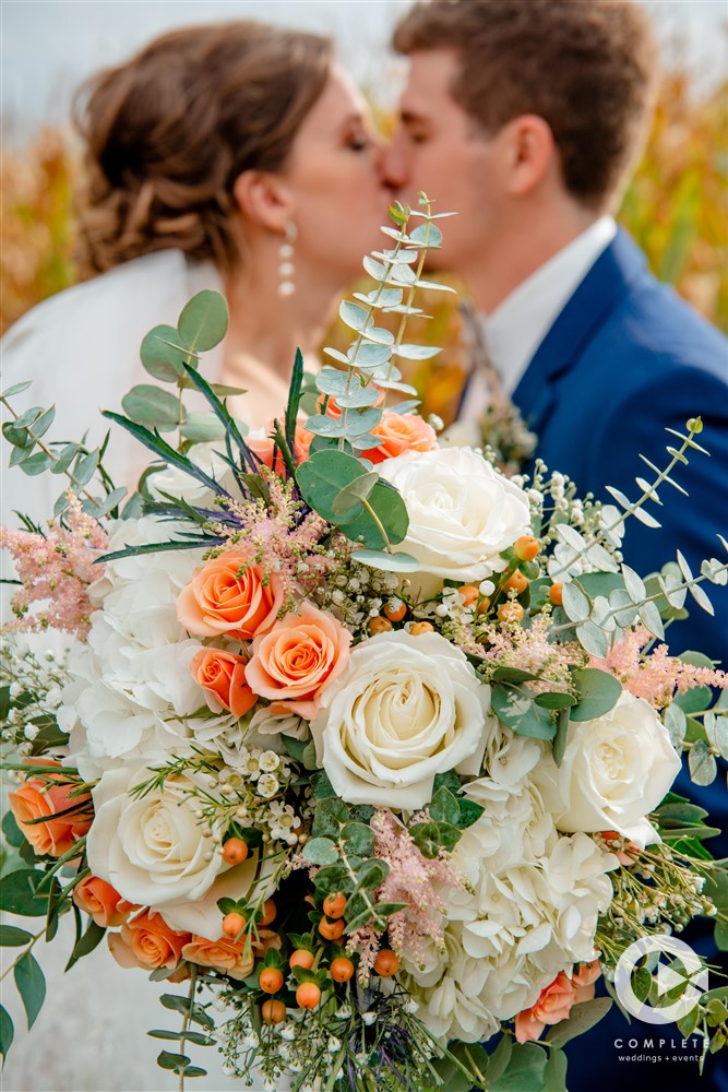Bride and groom kissing in Wisconsin while holding beautiful and colorful wedding bouquet