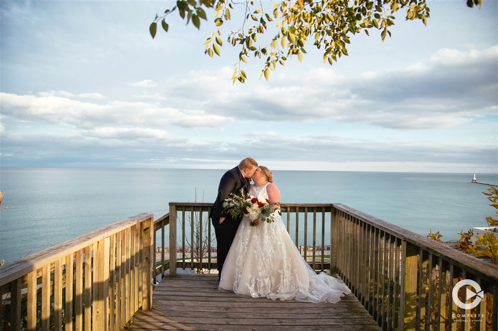 Bride and groom kiss on deck in front of Wisconsin lake