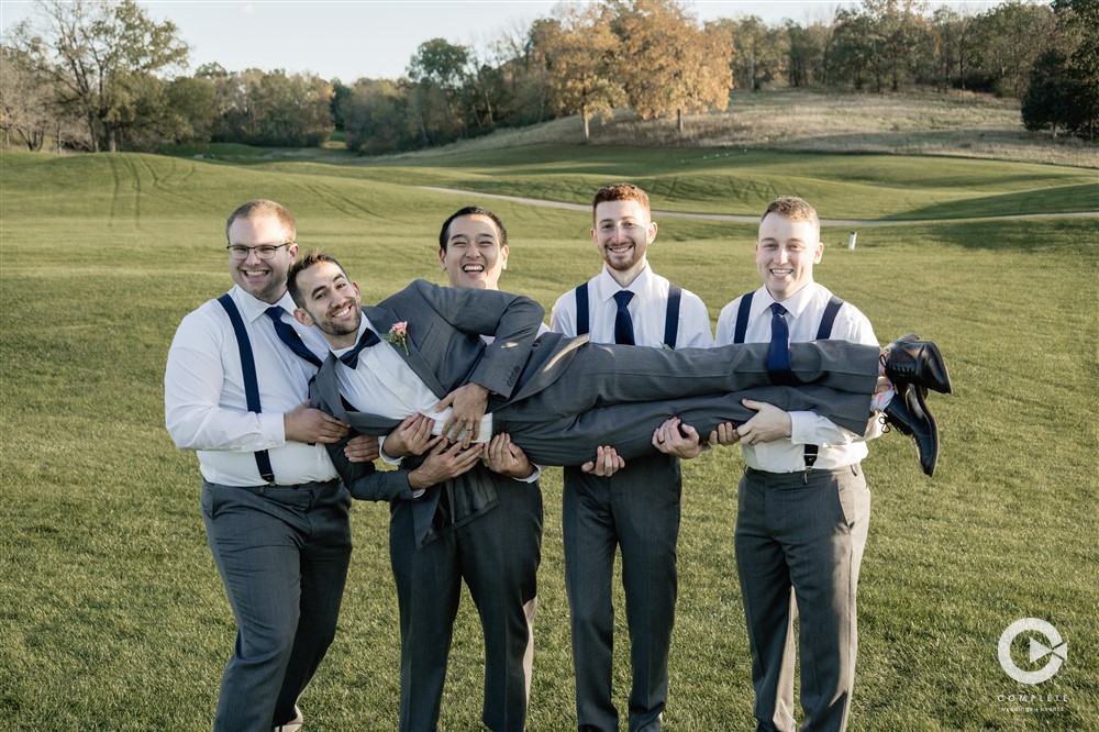 groomsmen carry groom
