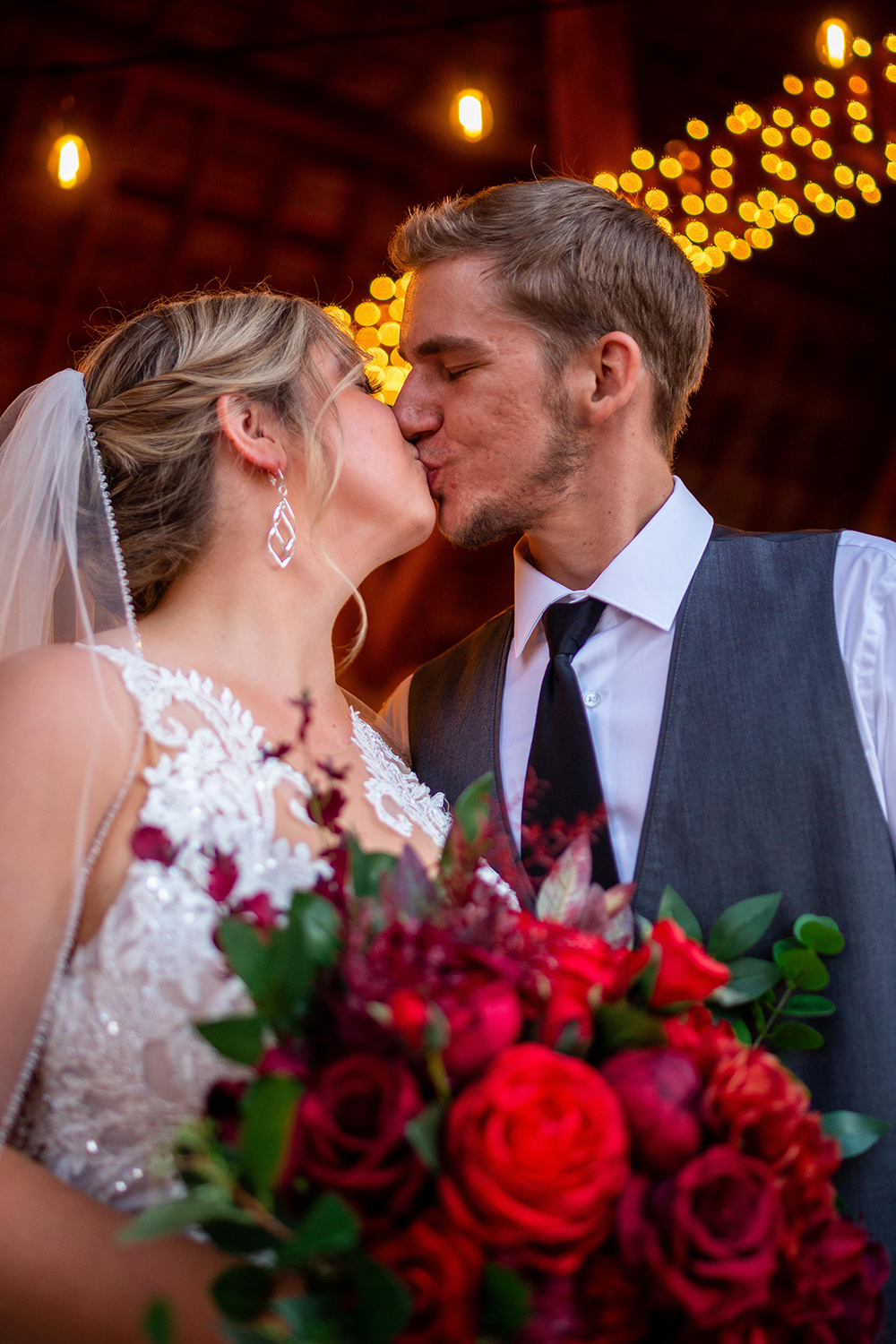 red bouquet & Bride and groom kiss at Milwaukee wedding