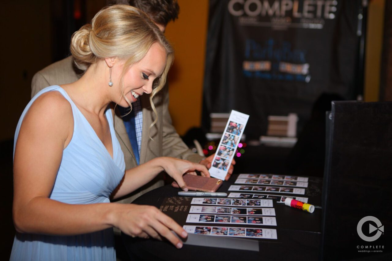 Bridesmaid smiles while adding her photo strip to the guest book to sign.
