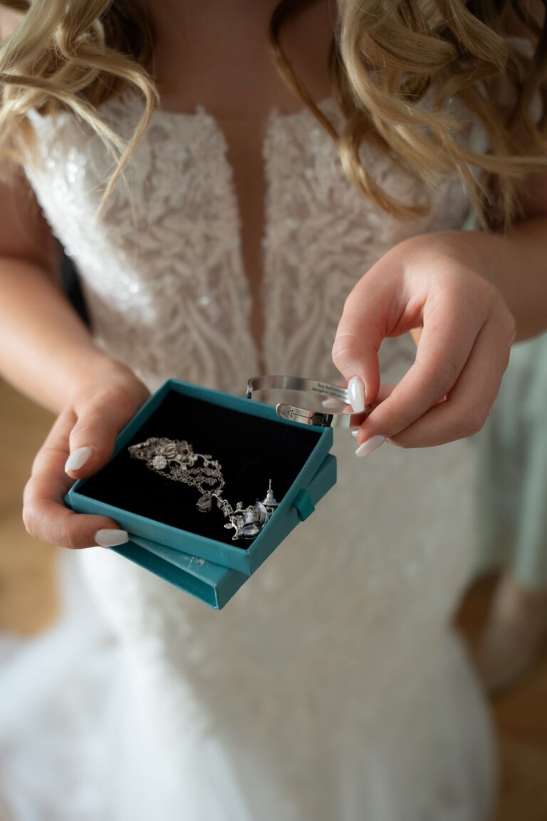 A bride removes her necklace from a blue jewelry box while getting ready for her wedding.