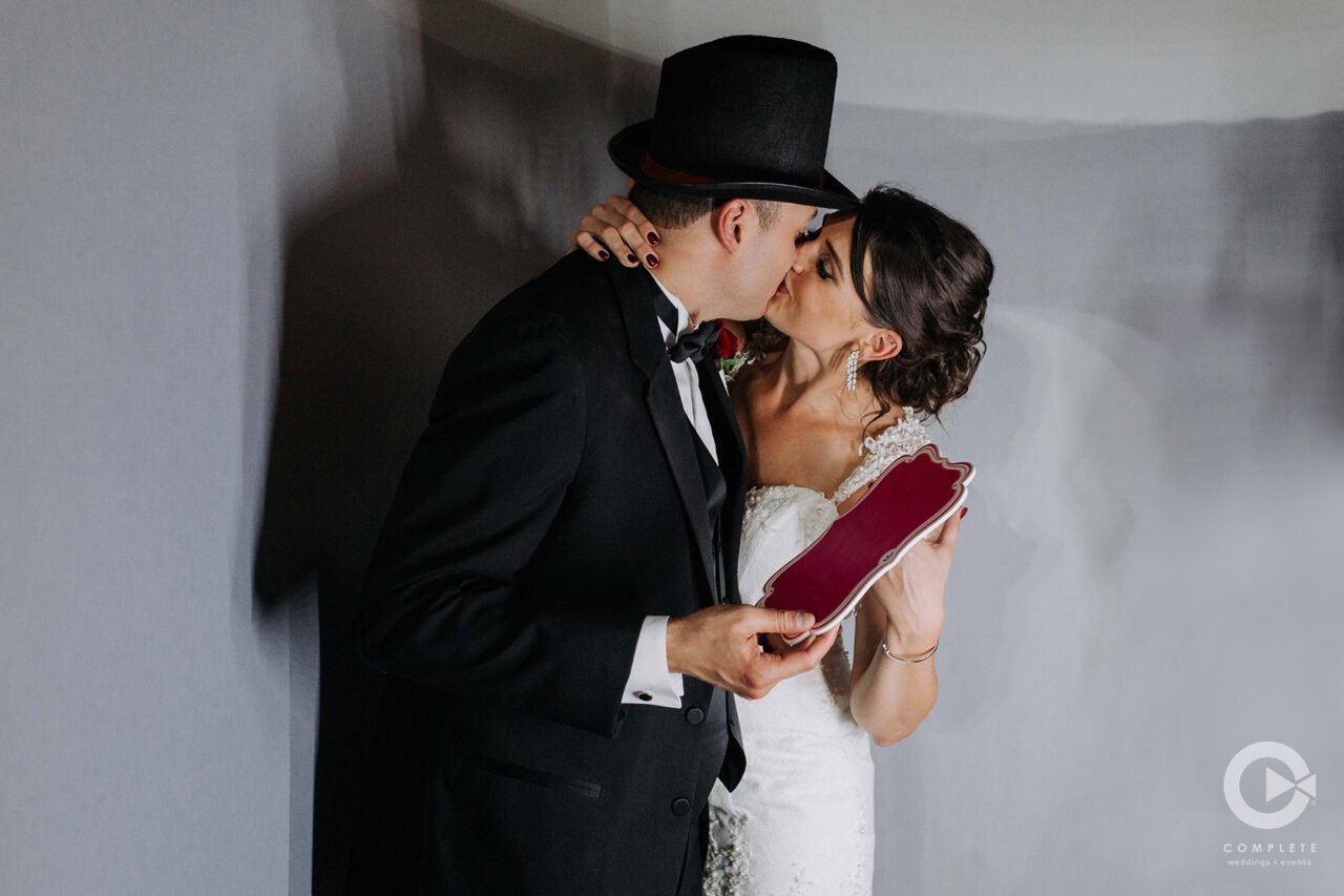 Bride and groom kiss in the light of the photo booth.