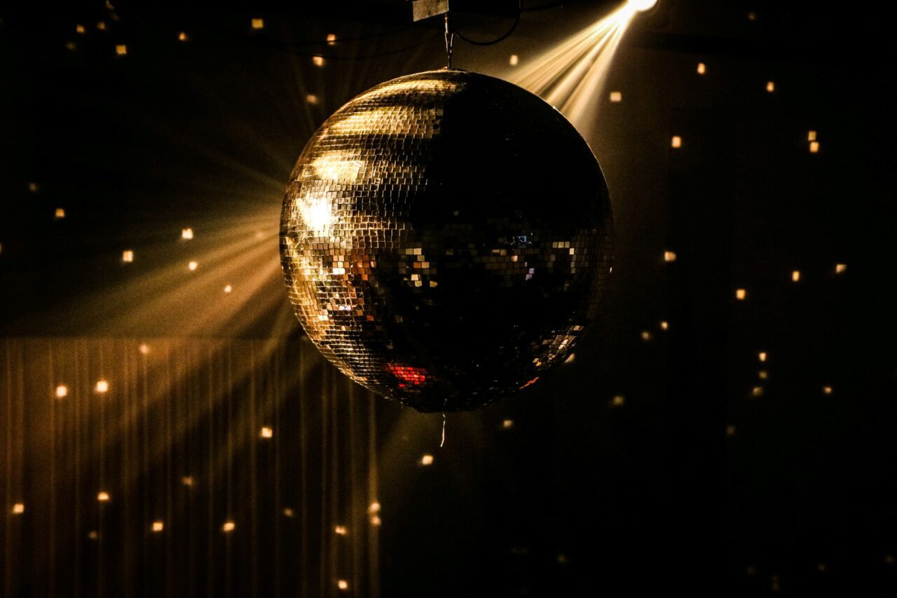 A disco ball illuminated by a spotlight, casting light patterns in a dark room.