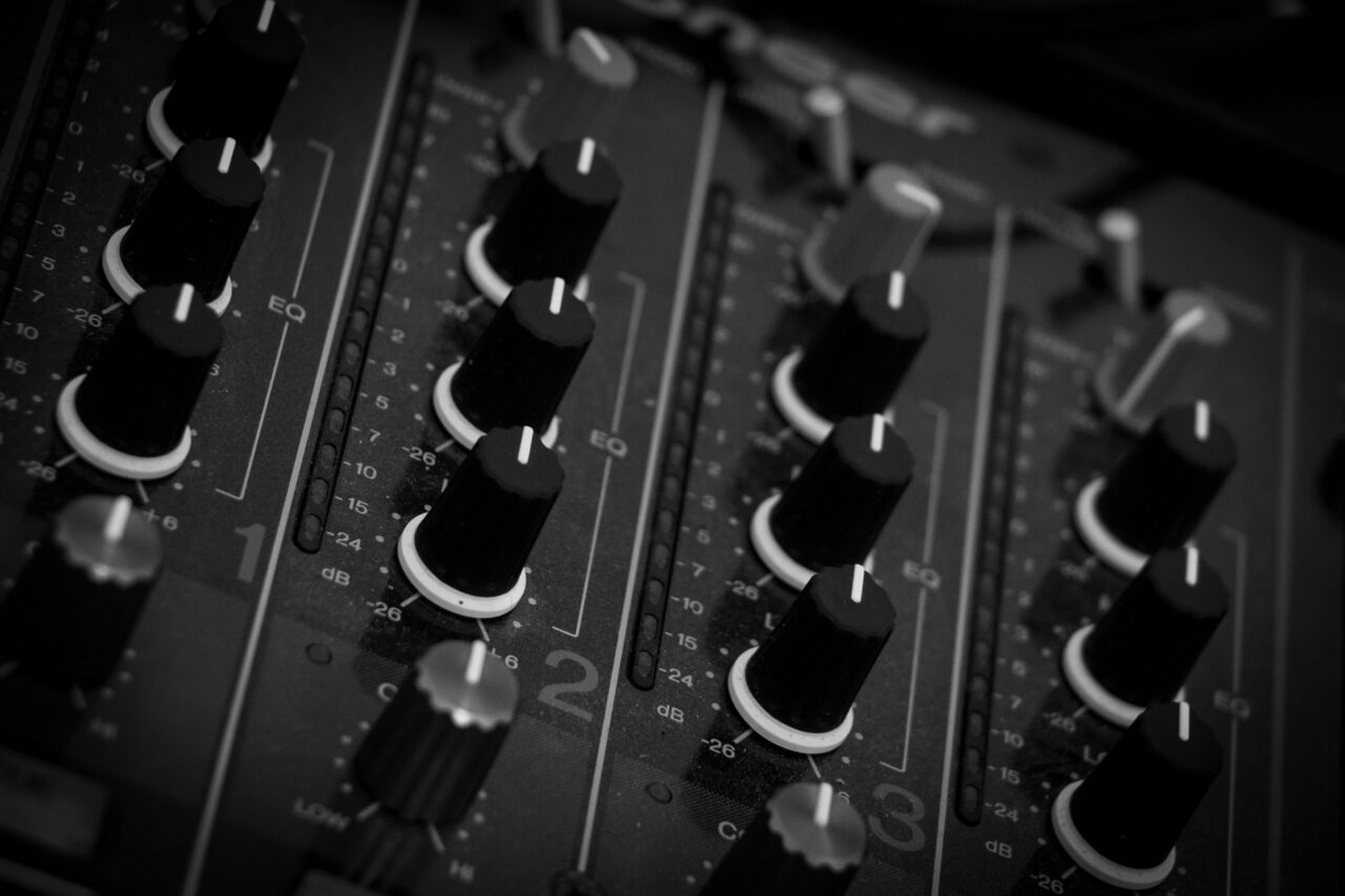 A close-up of a professional DJ mixing board with knobs and faders.