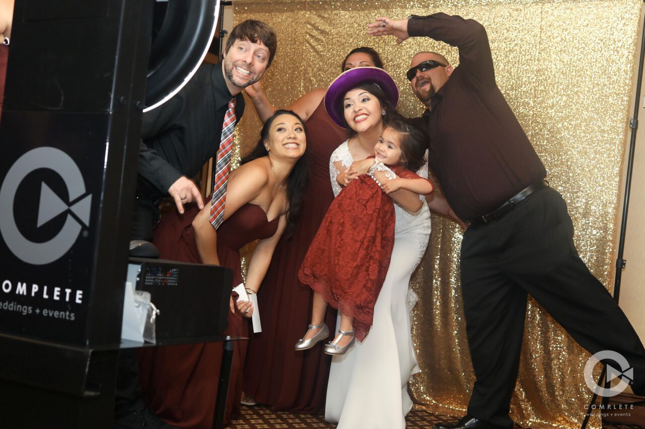 Nashville wedding guests smile, laugh and pose with props in front of a photo booth stand with a ring light.