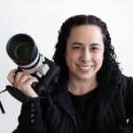 A professional headshot of wedding photographer Sammie O'Neal holding her camera and smiling.