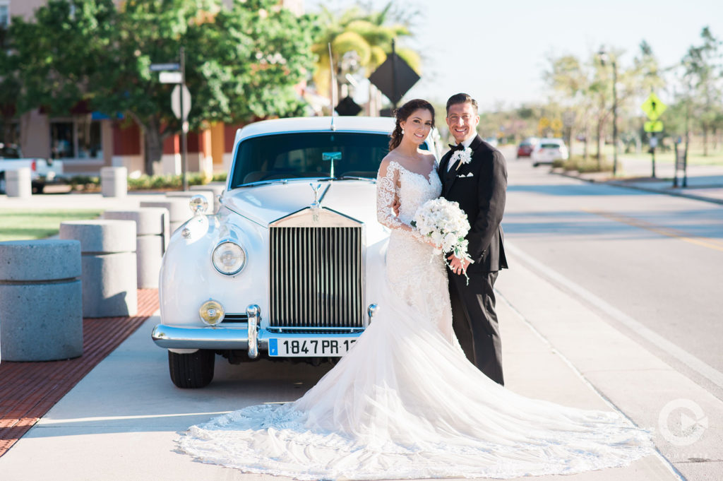 bride and groom standing in front of car