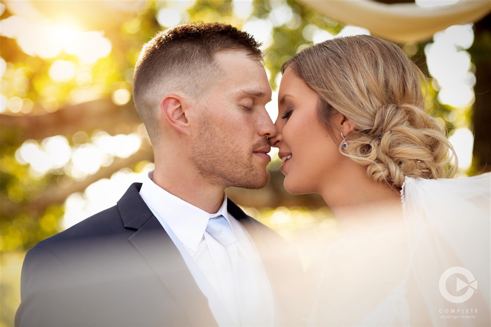 bride and groom kiss under tree