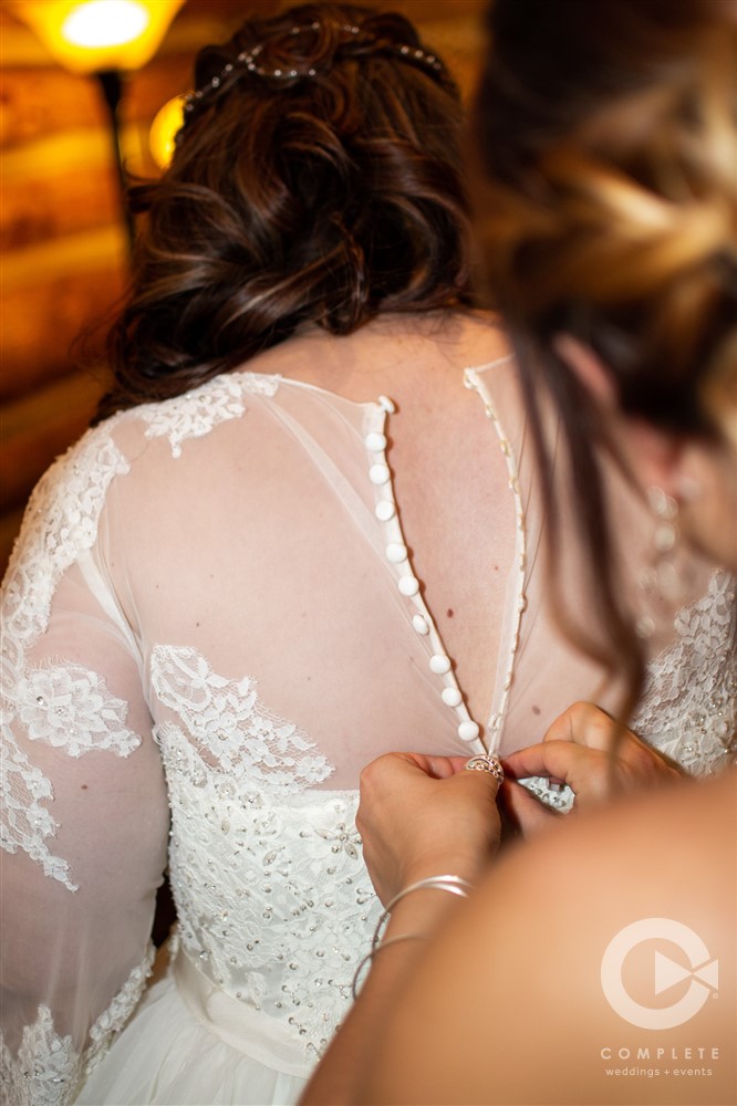 bride having dress buttoned up before ceremony