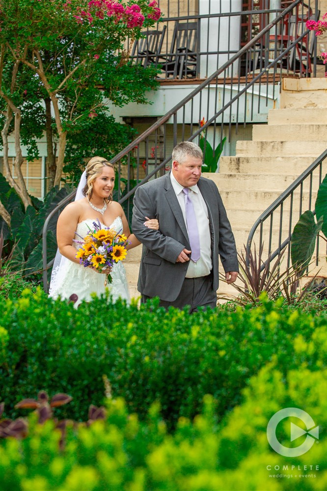 bride and father walk down the aisle behind hedge rows crescent hotel