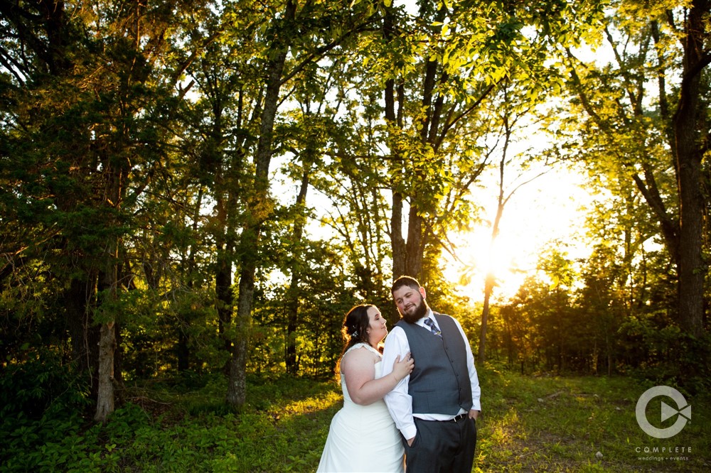 bride and groom in woods at sunset