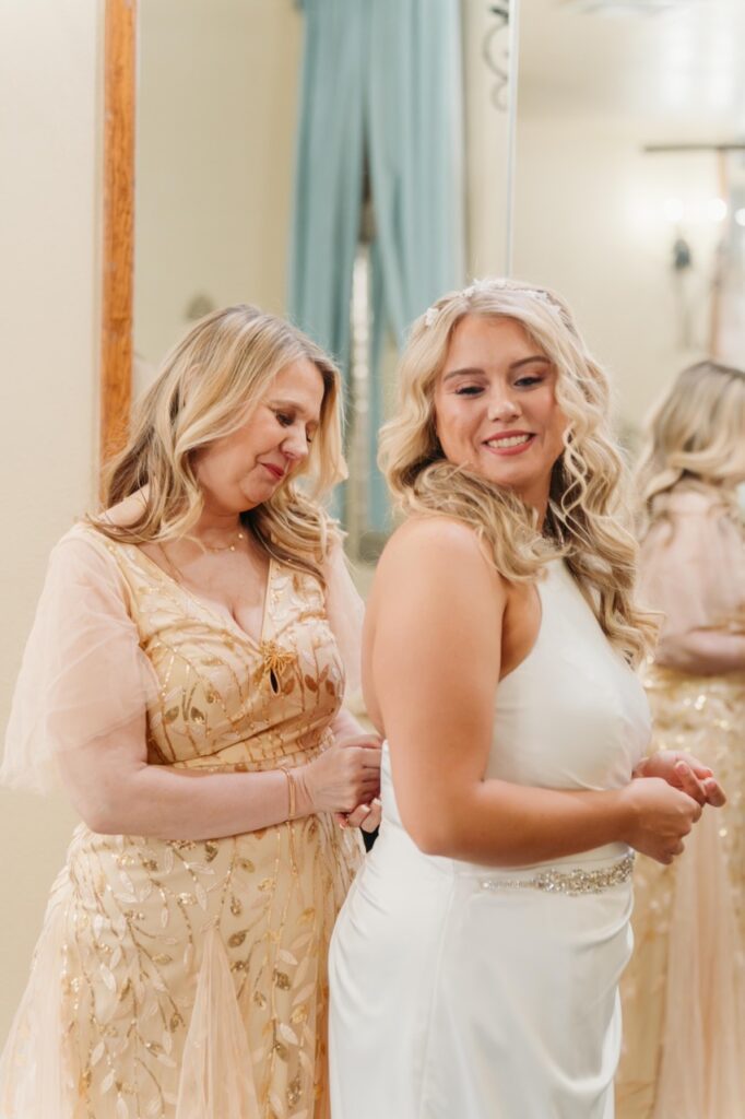 mom helping bride into dress