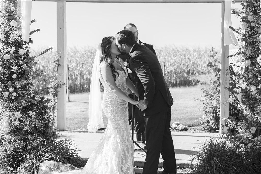 First kiss photo at the Farmhouse venue outside of Omaha with wedding photographer Cassie Burley