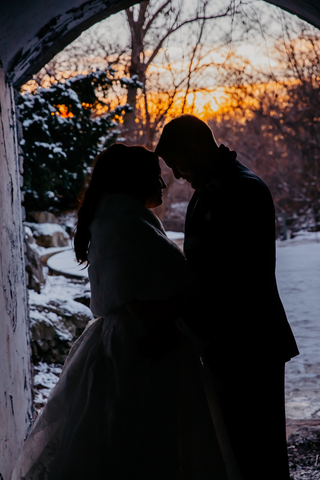 Dark photo of a couple at the end of a tunnel while sun sets behind them