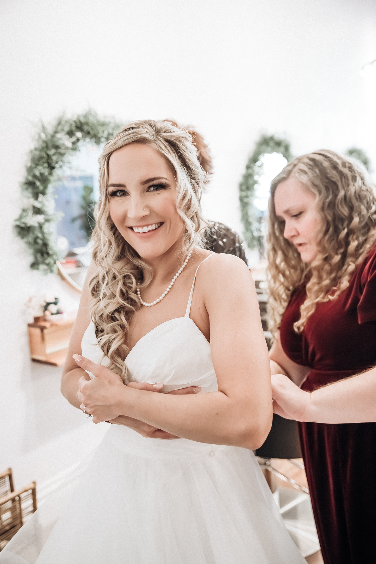 Wedding photo of a bride getting her dress zipped up in Omaha Carmen photographer
