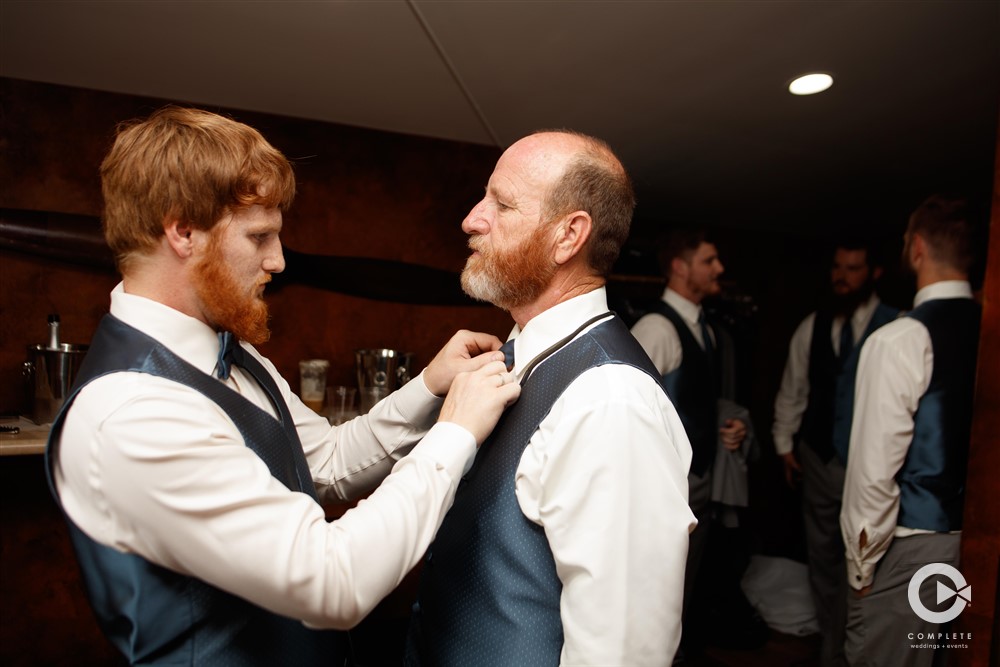 groom helping groomsmen tie his bowtie